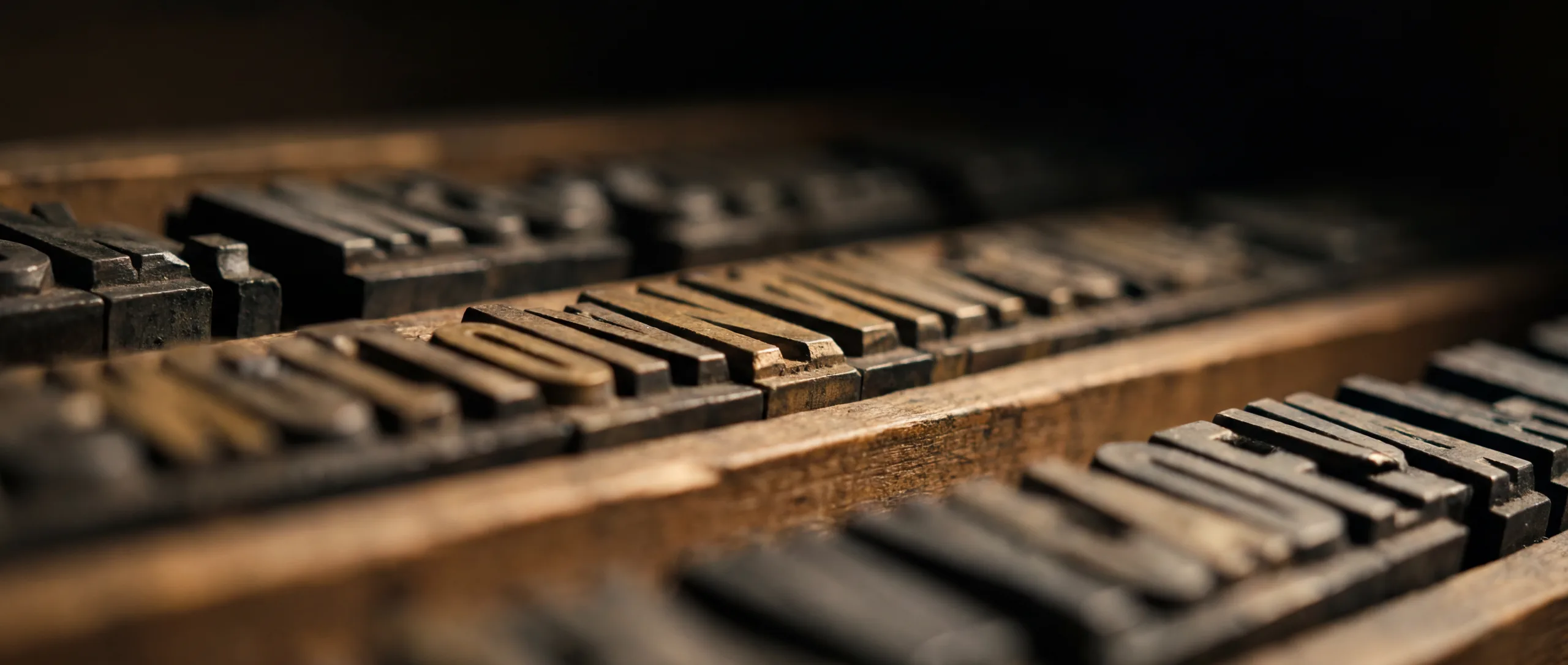 Rows of vintage metal letterpress type in a wooden printer’s tray
