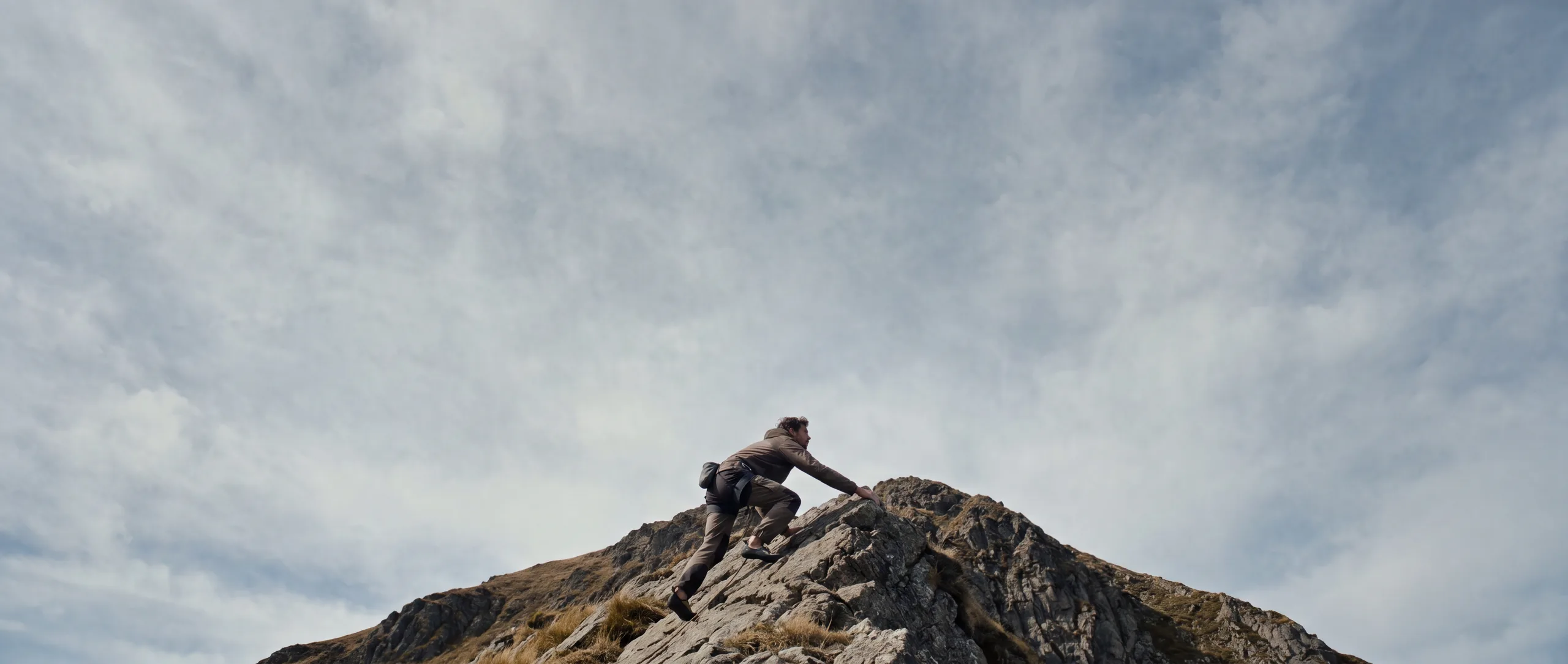 A lone climber nearing a granite summit at first light